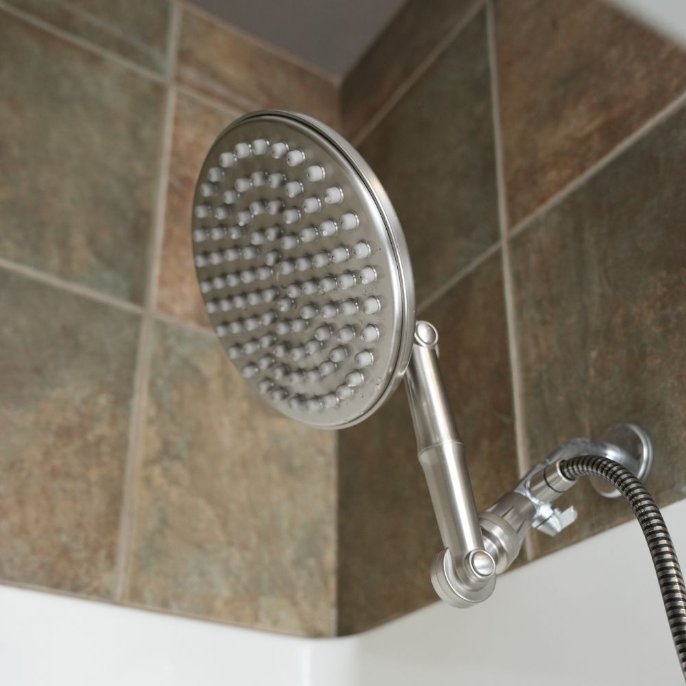 Brushed Nickel shower head mounted on a tiled bathroom wall