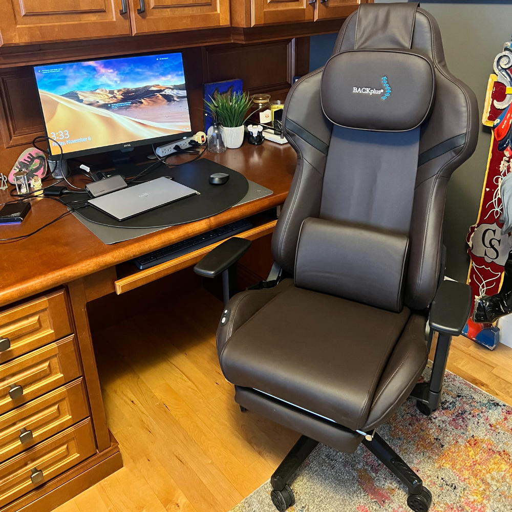 A leather office chair beside a wooden desk with a computer setup. The cozy workspace features a potted plant and colorful decorations, creating a warm, inviting atmosphere.