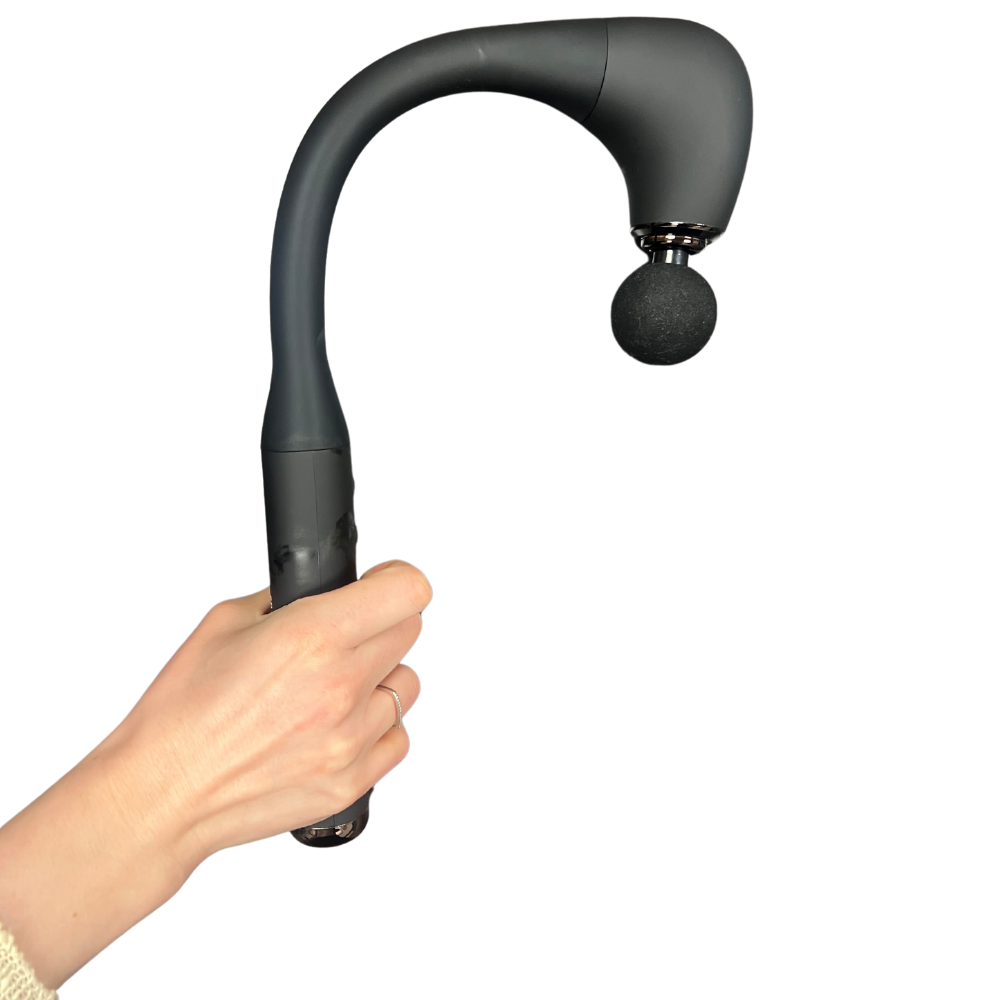 A hand gently holds a BACKplus hammer full body massager with a round attachment head against a white background. The device conveys a sense of relaxation and ease.