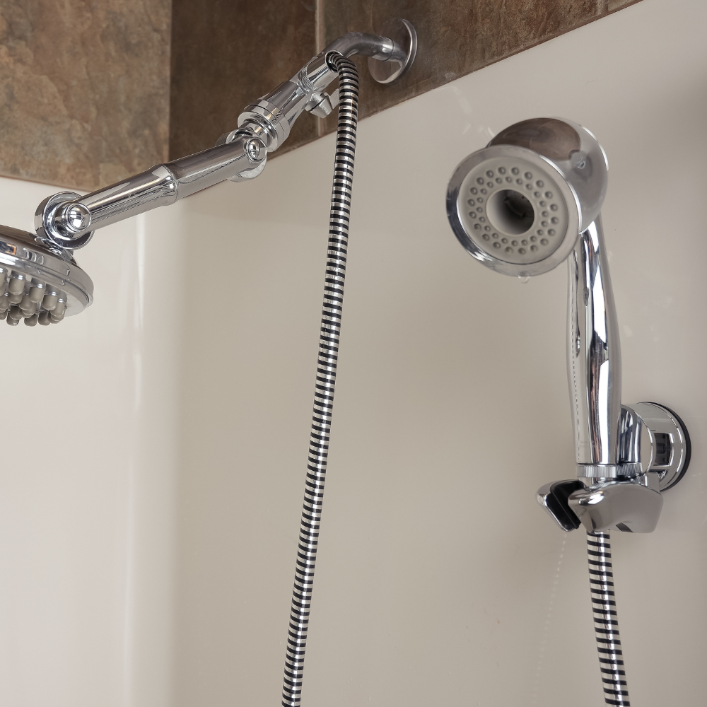 Two chrome shower heads with adjustable arms and hoses are mounted on a tiled wall, conveying a clean and modern bathroom aesthetic.