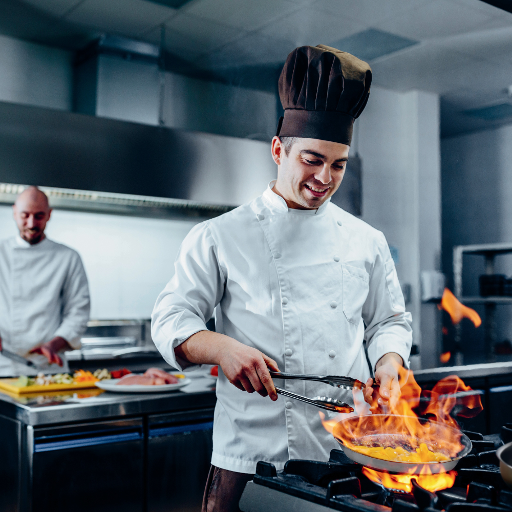 A chef using Qooks Cookware in a Kitchen. Qooks pan on stovetop cooking a fresh, hot meal.