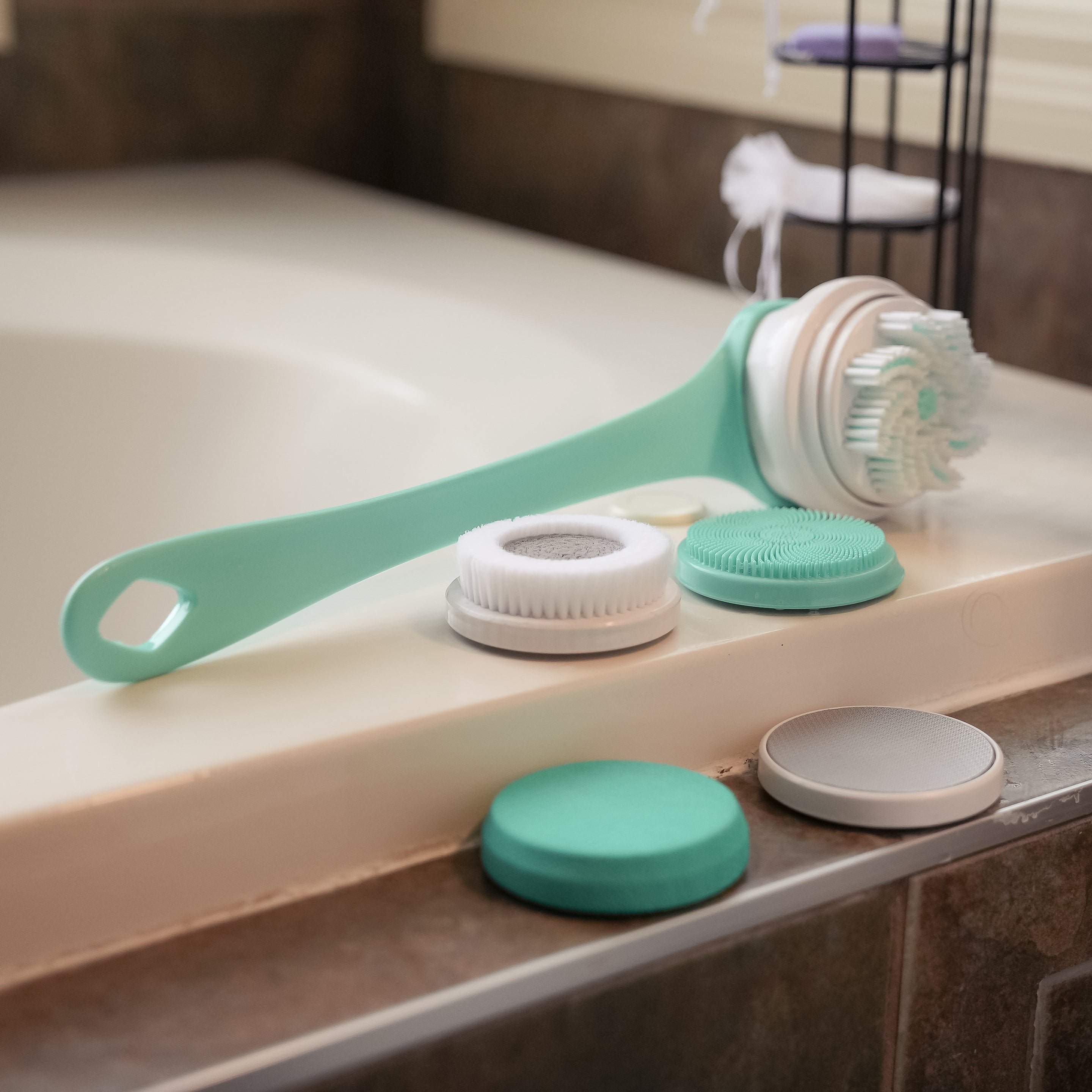 Multifunctional Electric Shower Brush and included attachments beside a bathtub in teal.