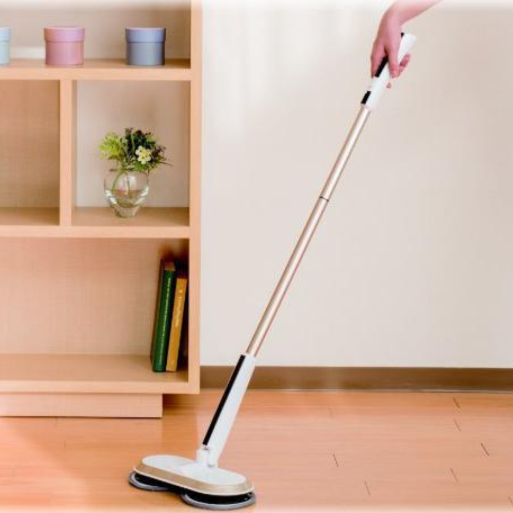 A person holds a Rocket Mop, standing next to a wooden shelf with colourful boxes and books in a clean room.