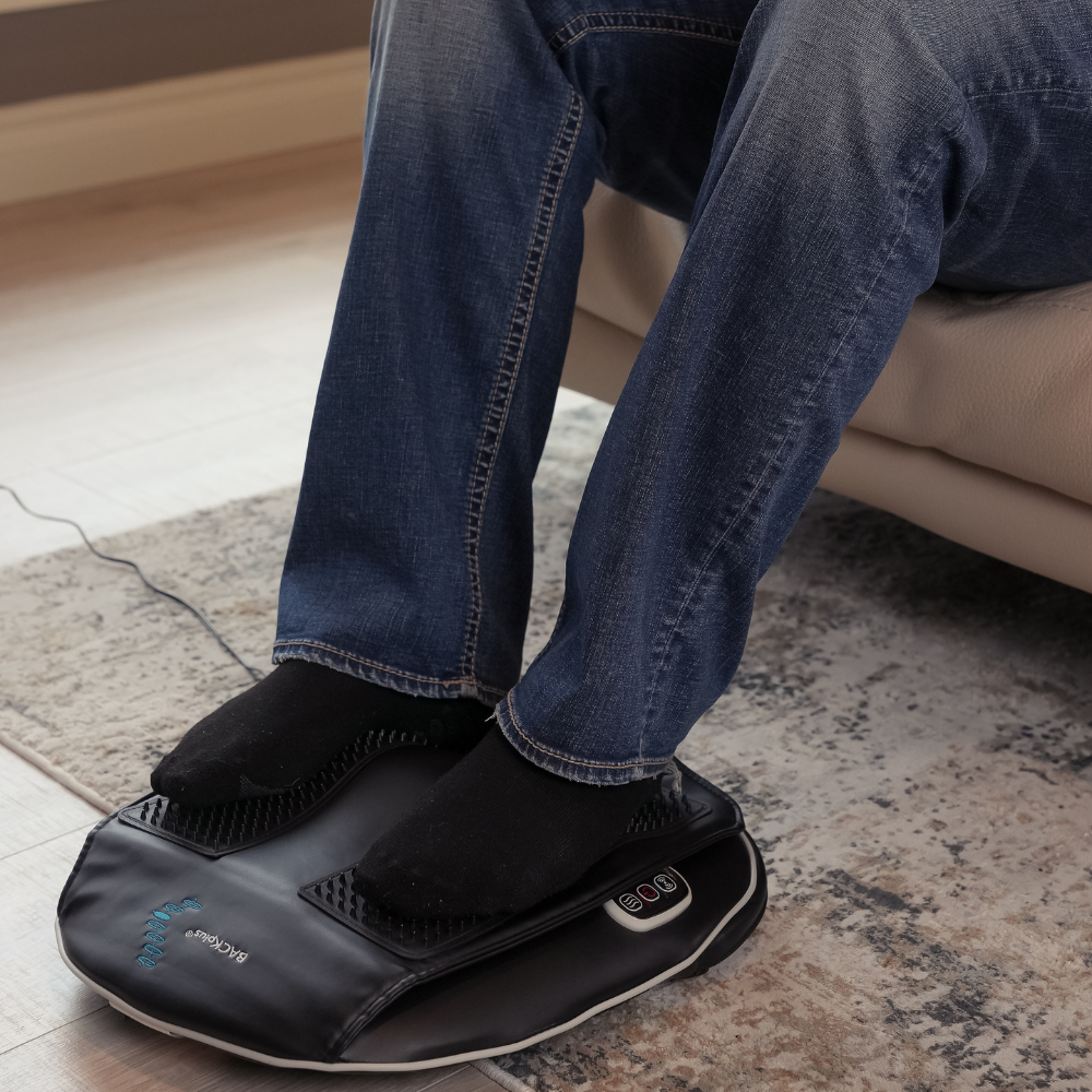 Man sitting on a beige couch using the BACKPlus® Shiatsu Back and Foot Massager on his feet