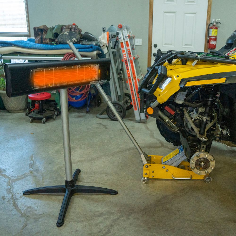 Portable infrared heater next to a yellow snowmobile in a garage.