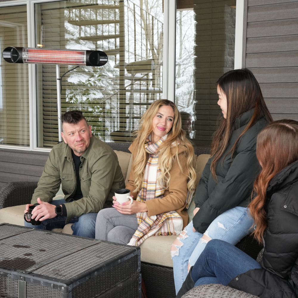 A cozy gathering on a covered porch, featuring four friends seated on a couch with a coffee table, surrounded by snowy scenery with an infrared heater keeping them warm.