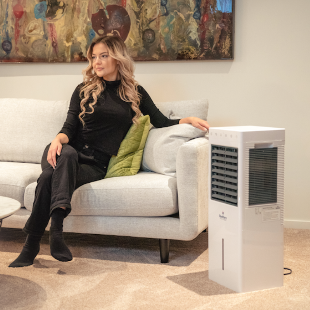 Woman sitting on her couch enjoying the iQ Pure Breeze Air Cooler