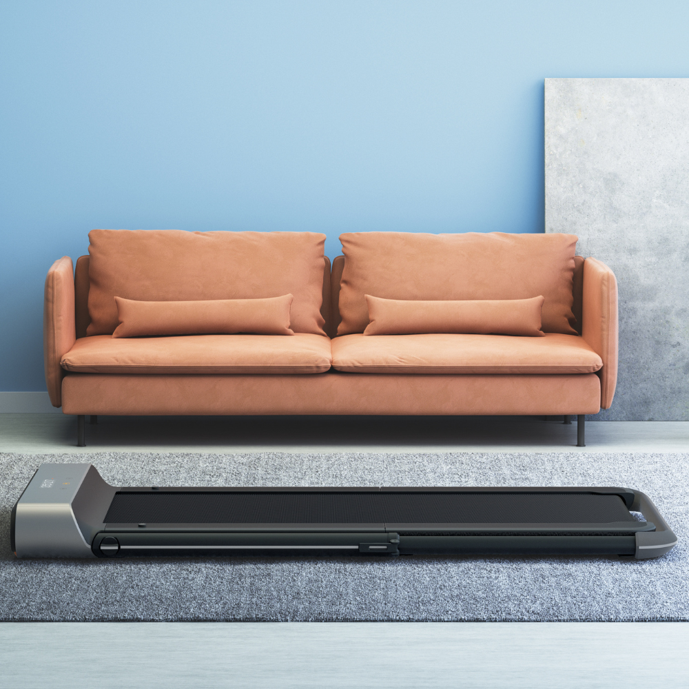 iQ Slim Tread® Foldable Treadmill in front of a couch