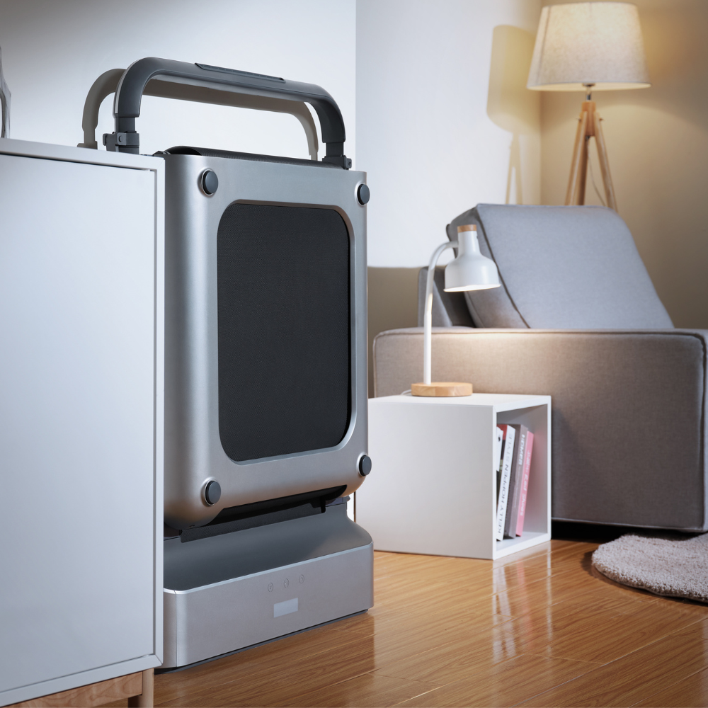 iQ Slim Tread® Foldable Treadmill stored in folding position beside chair