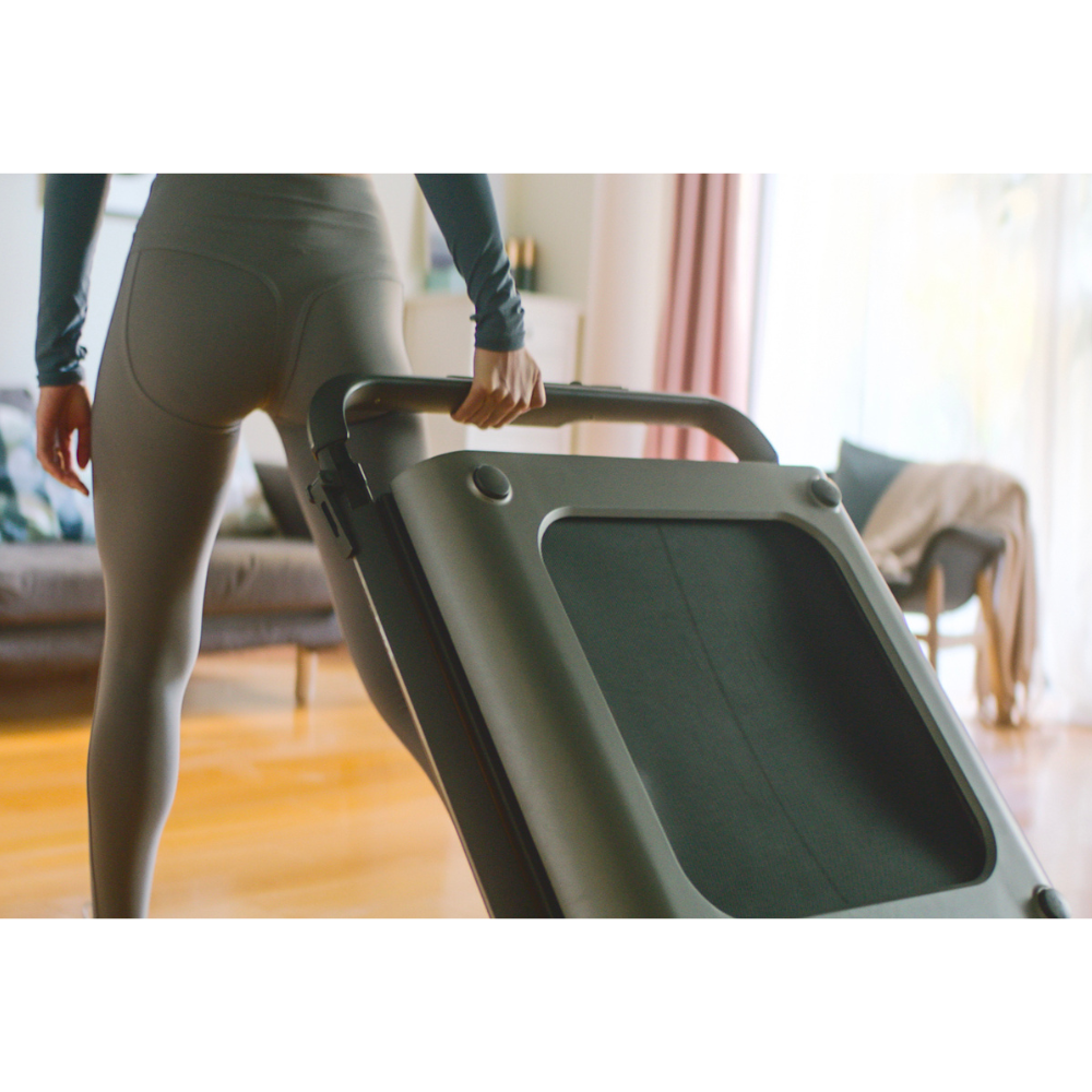 Woman moving her iQ Slim Tread® Foldable Treadmill in folded position