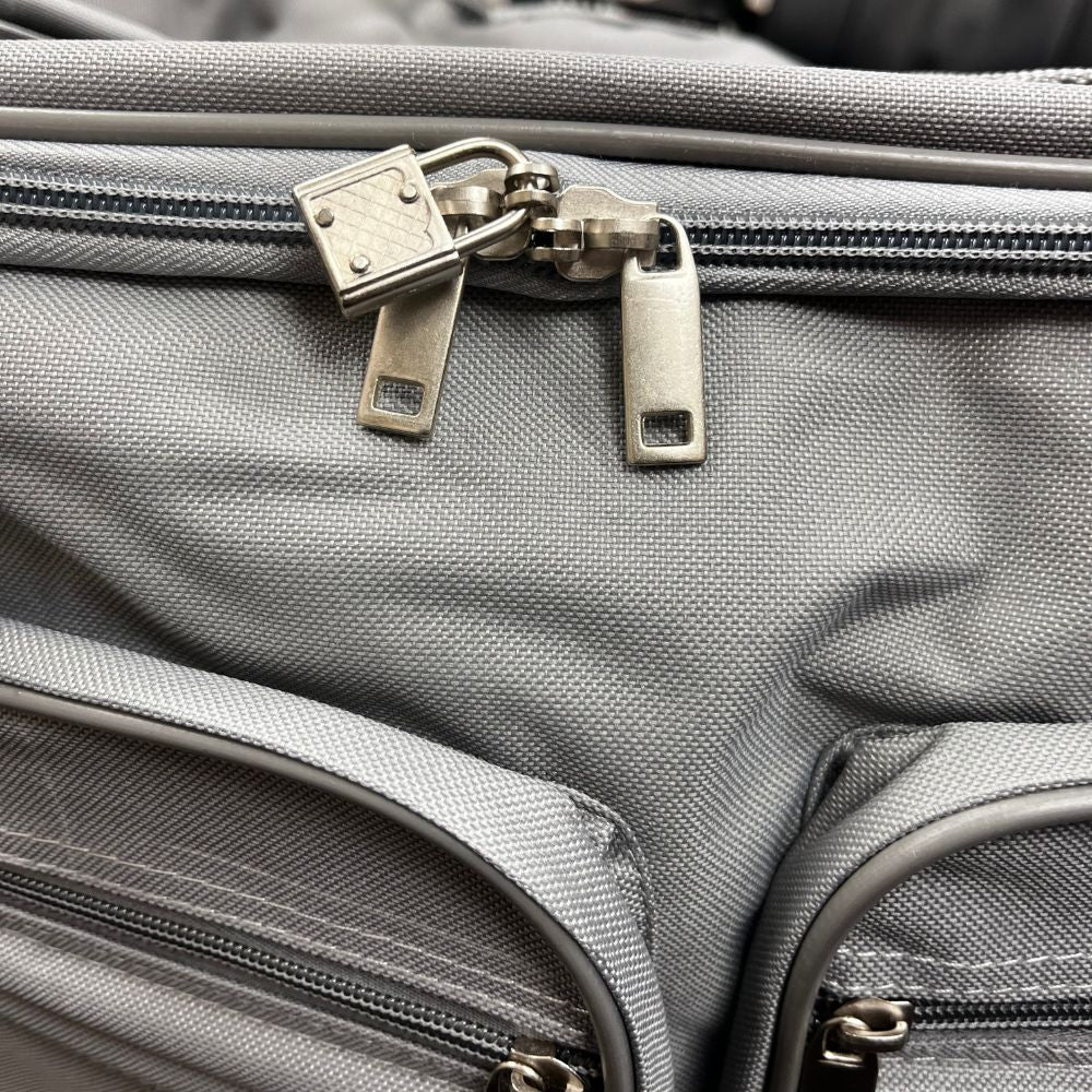 Close-up of a gray suitcase with a nickel zipper and lock.