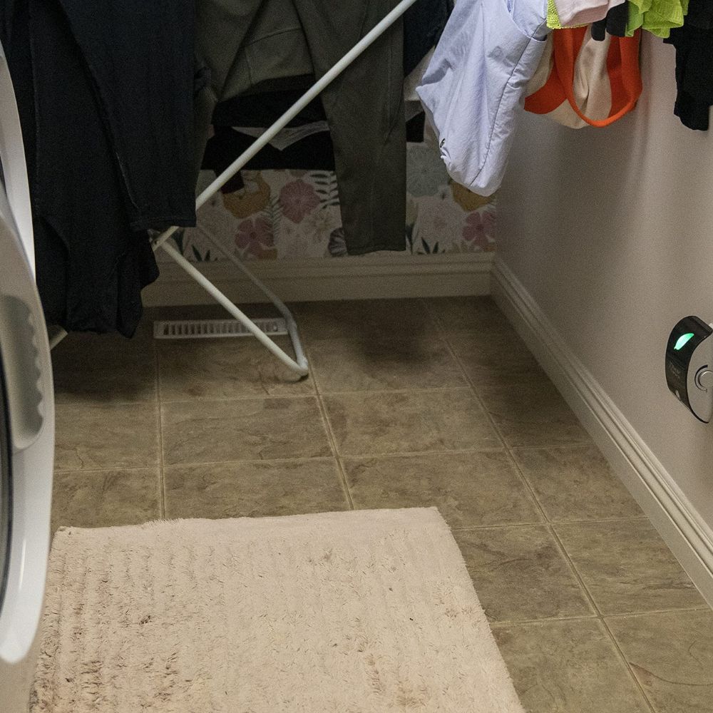 Laundry room with clothes on a rack, tiled floor, and washing machine with iQ Pure Air Purifier