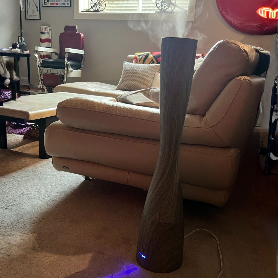 Floor-standing humidifier in a living room with a beige sofa and coffee table.