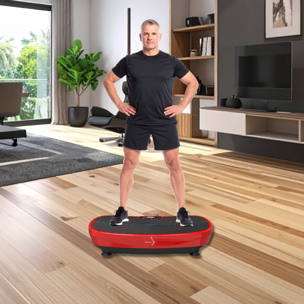 A man in black athletic wear stands confidently on a red vibrating platform in a modern living room, exuding energy and determination.