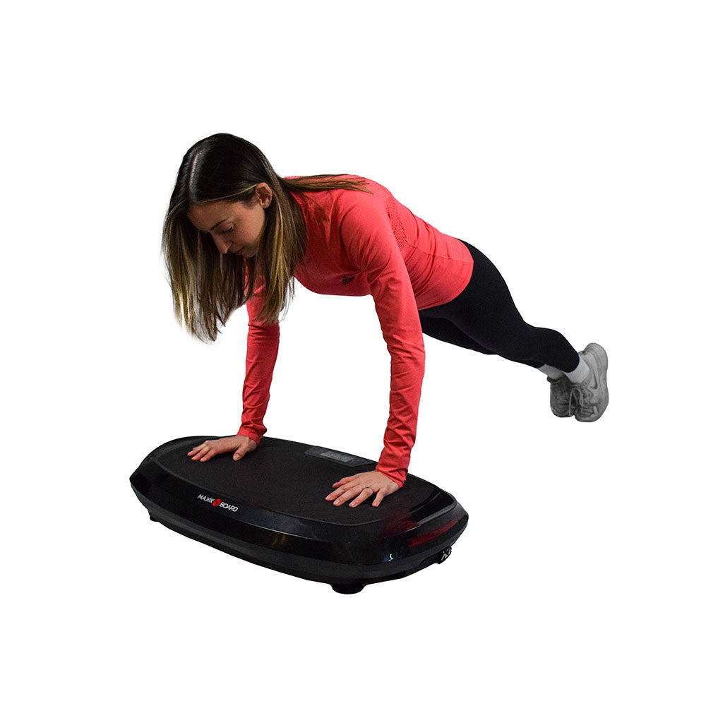 A person performs doing push ups on a fitness balance board, wearing a pink long-sleeve shirt and black leggings.