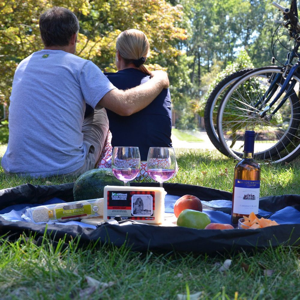 Couple enjoying a picnic with wine and food on a Nifty Sac in a park.