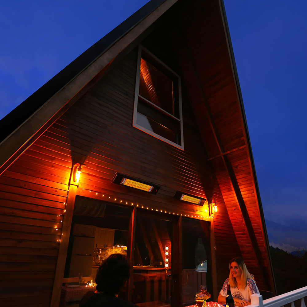 Wooden cabin with warm lighting at night, people sitting on a porch with the Veito Aero Heater.