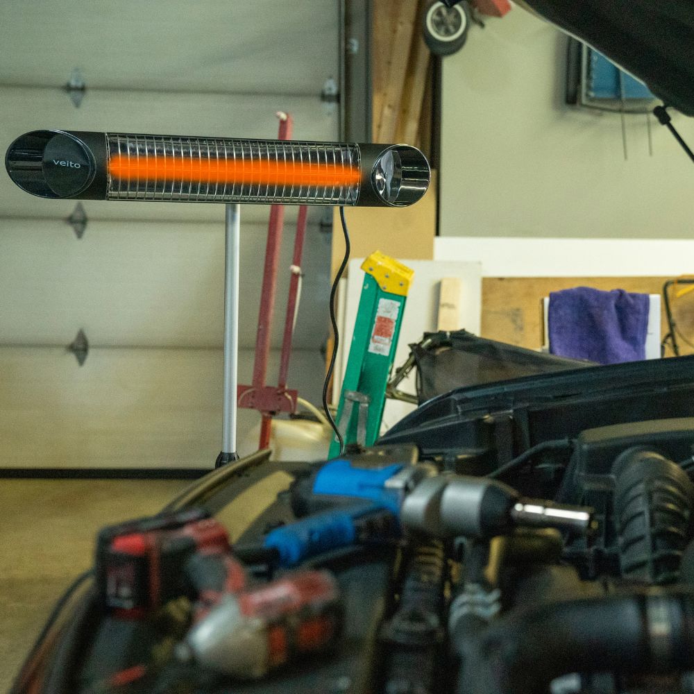 Infrared heater on a stand in a garage with tools and equipment around