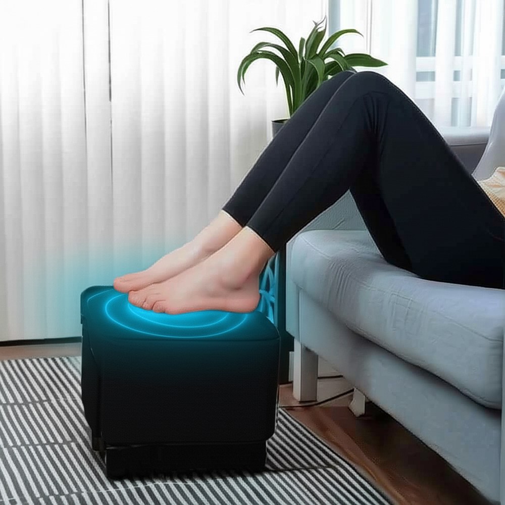 Person with feet on top of Ottoman foot massager placed in a living room next to a sofa